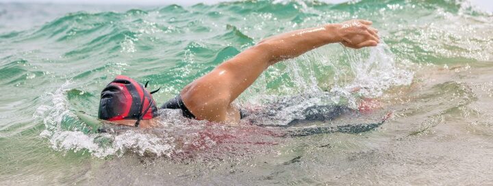 swimmer with red cap on in ocean