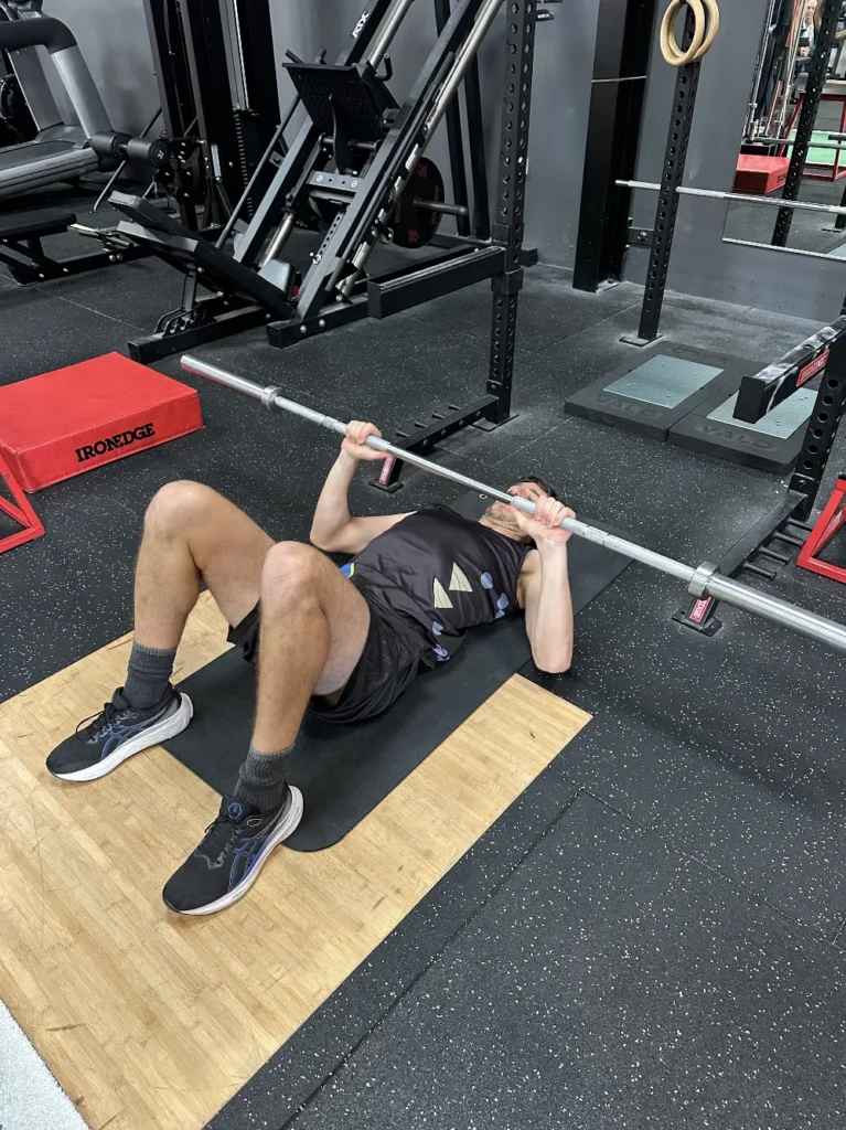 Barbell floor press to limit depth and reduce shoulder strain