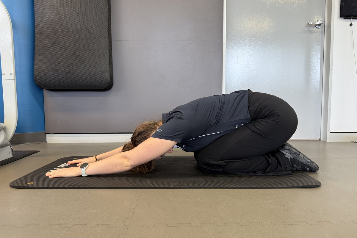 Person performing a child's pose stretch on a mat
