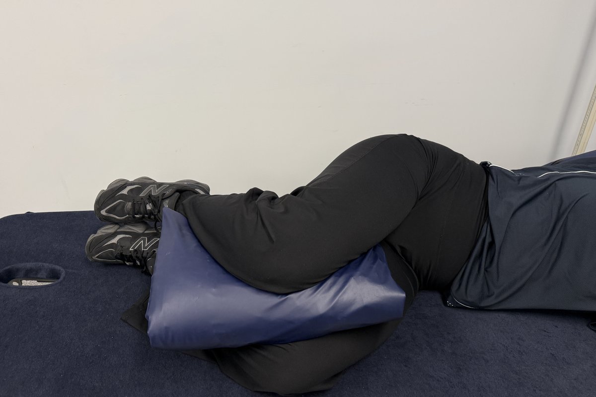 Person side lying in bed with a pillow placed between the knees