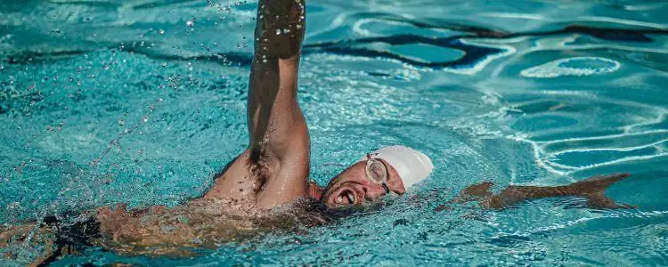 Freestyle swimmer turning his head to breathe with one goggle in the water