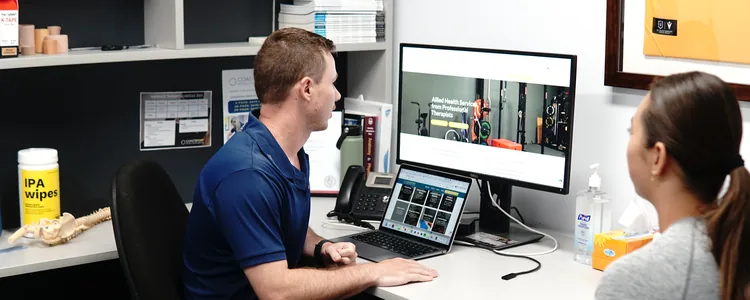 Physiotherapist talking with a patient at a clinic desk