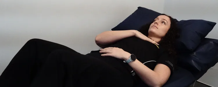 Woman practising diaphragmatic breathing lying on her back with one hand on her chest and one on her belly